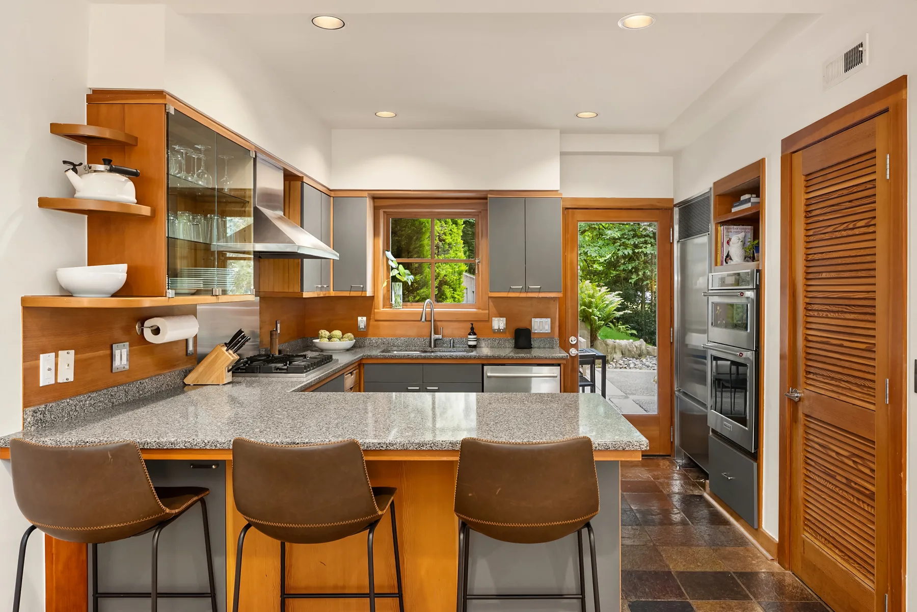 Kitchen with granite countertops, glass-front cabinetry, and a U-shaped breakfast bar
