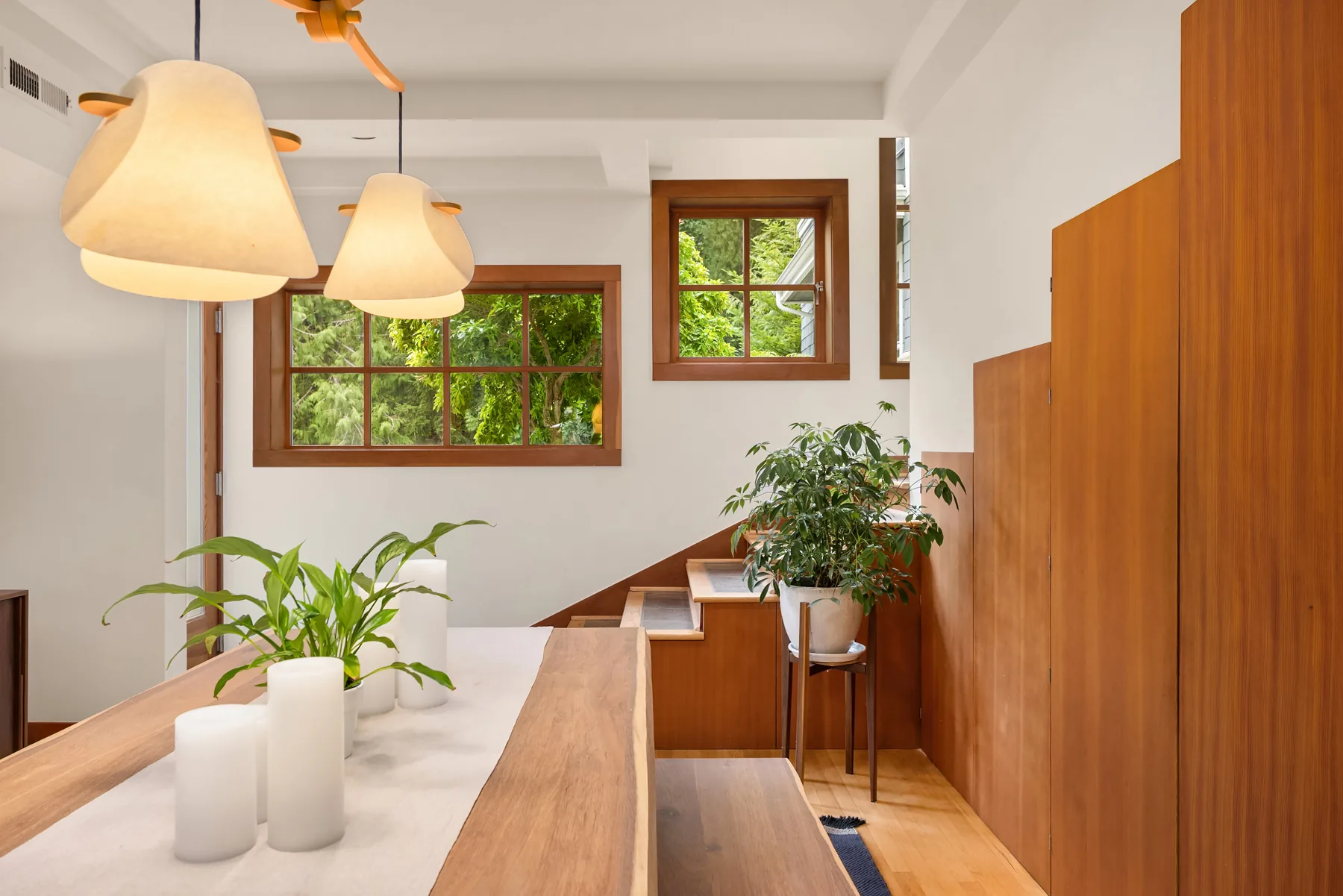 Dining area with live-edge table, pillar candles, and sculptural paper pendant lights