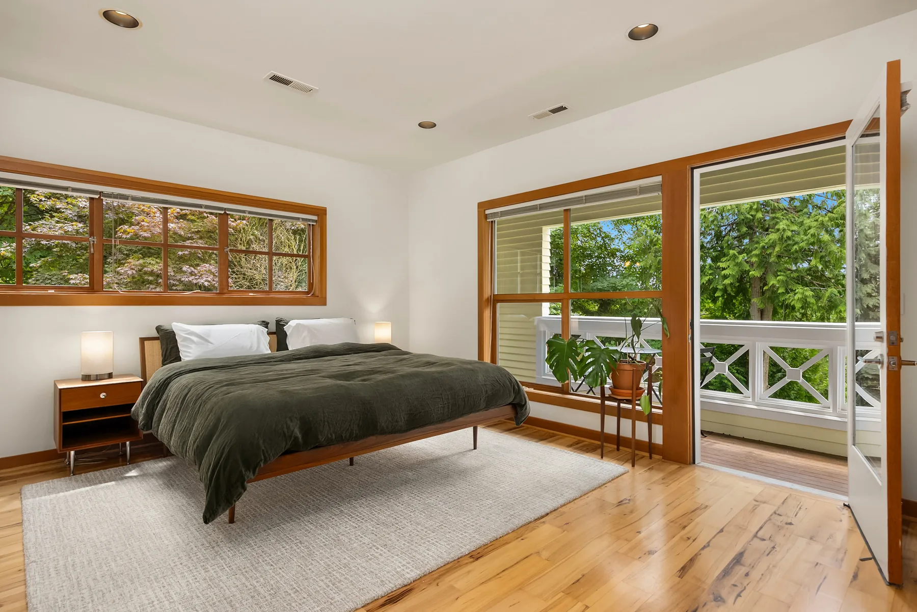 Primary bedroom with door to the balcony and treetop views