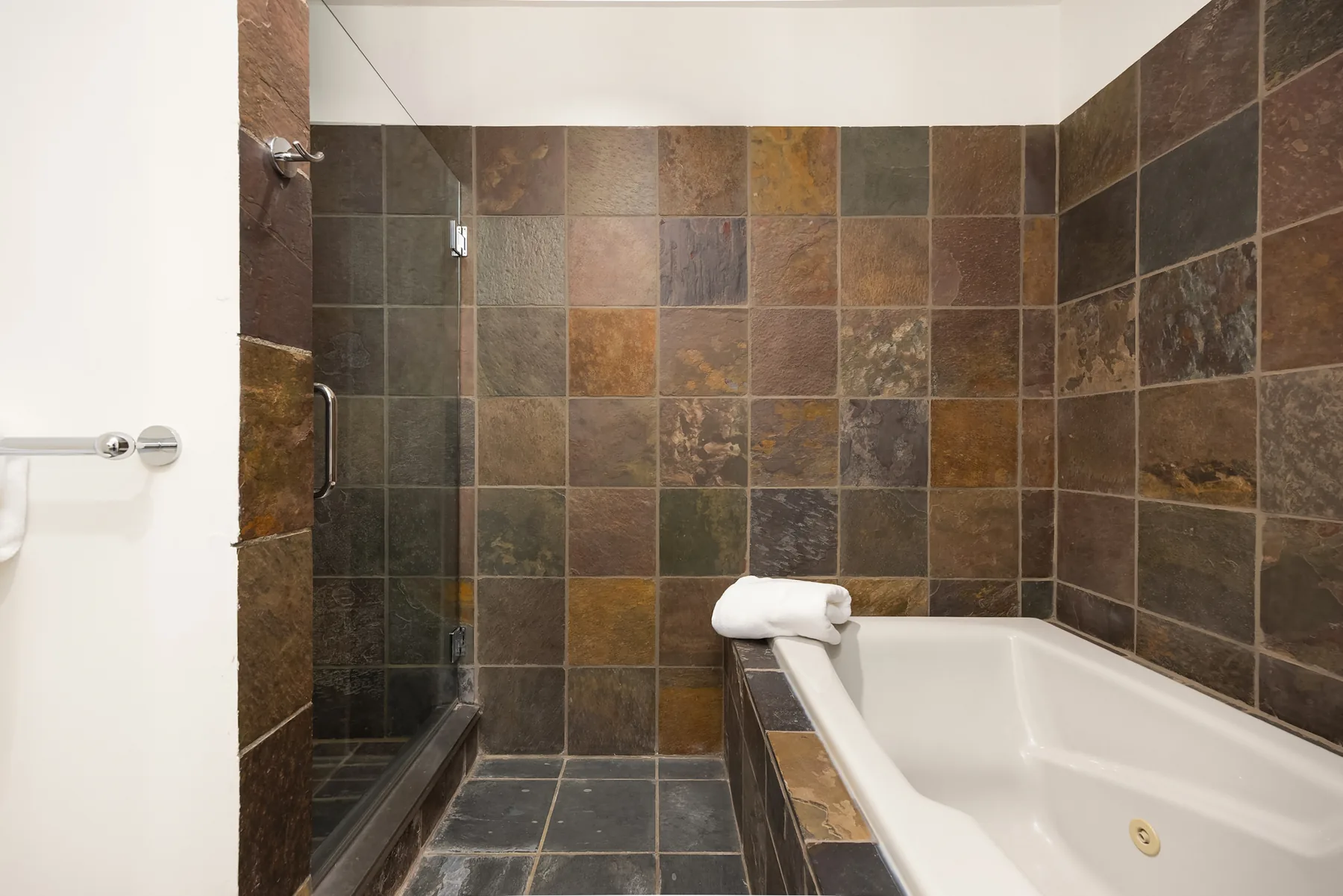 Slate-tiled shower and soaking tub in the primary bath