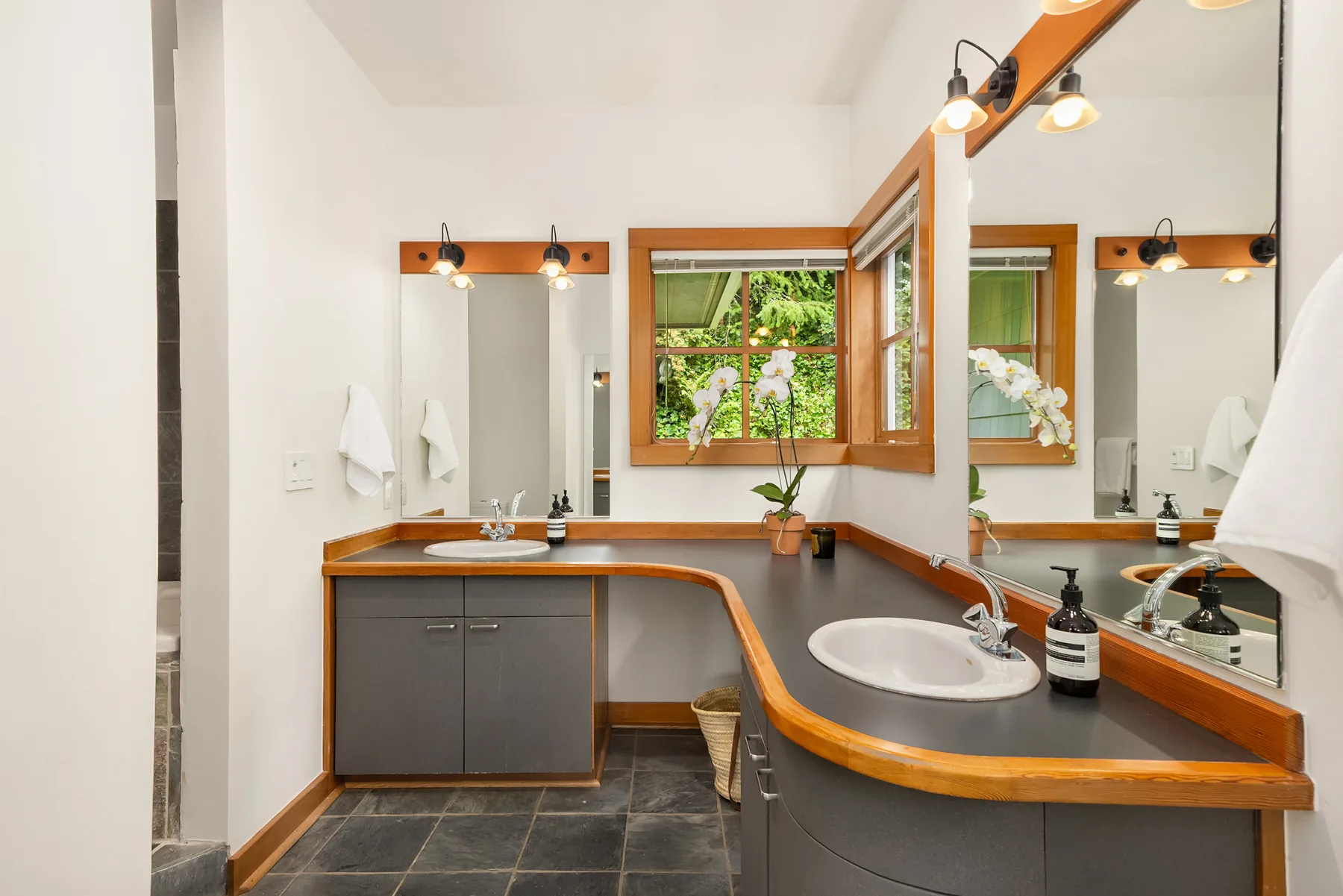 Primary bathroom vanity in Douglas fir trim with twin mirrors and orchid